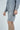 Someone wearing a Charcoal Gray Deerfield Hoodie, made from ultra-soft cotton with a comforting fleece lining, poses against a white background. Their matching shorts complete the look as hands rest casually by their sides, showcasing the outfits laid-back comfort.