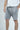 A person wears Deerfield Short Charcoal Gray, featuring easy glide pockets, loose fit, visible stitching, and drawstring. The charcoal shorts complement a crisp white shirt against a plain backdrop, highlighting the outfits relaxed style.