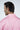 A man with dark hair faces away in a pink collared shirt made from luxury performance fabric. JAXSON MAXIMUS is embroidered on the back, showcasing its bespoke English spread collar. The plain white background enhances the stylish appeal of the West Palm Polo: Dolphin Tail Pink.