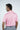 A man with dark hair faces away, wearing a West Palm Polo in Dolphin Tail Pink and gray pants. The image captures him from behind, showcasing the luxury performance fabric against a simple, light-colored background.