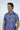 A man smiles and looks to the side, wearing a short-sleeved Panhandle Polo from Jaxson Maximus, the print is "Keys Coral Reef", a vibrant purple with pink and yellow floral patterns. Made from breathable Micro-Pique, its perfect for staying cool.