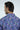 A dark-haired man faces away, donning a vibrant, wrinkle-resistant Panhandle Polo: Keys Coral Reef with a colorful abstract floral pattern in blue, purple, and pink. Mason-Maximus is printed near the collar on this Micro-Pique design.