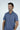 A person in a wrinkle-resistant Panhandle Polo: Tropical Oasis smiles confidently against a plain white background, their neatly styled dark hair enhancing their relaxed posture with hands by their sides.