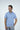 A person wearing the short-sleeve Panhandle Polo: Gulf Coast Turtle with a blue pattern and gray pants smiles, looking to the side with hands in pockets. The breathable Micro-Pique fabric ensures comfort against a plain white background.