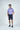 A man in a Jaxson Maximus Sarasota Polo: Golf Cart Palm Purple. His outfit includes a dark braided belt and navy shoe.