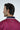 A dark-haired man slightly faces away, highlighting the Sarasota Polo: Golf Girl Ruby jacket made of luxury performance fabric with a red and black pattern and four-way stretch. JAXSON MAXIMUS is displayed on the back against a plain white backdrop.