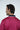 A person with dark hair, turned slightly left, wears the Sarasota Polo: Shark Attack Ruby. The red shirt is crafted from luxury performance fabric with a black pattern and dark collar. It features a name and logo on the back against a plain white background.